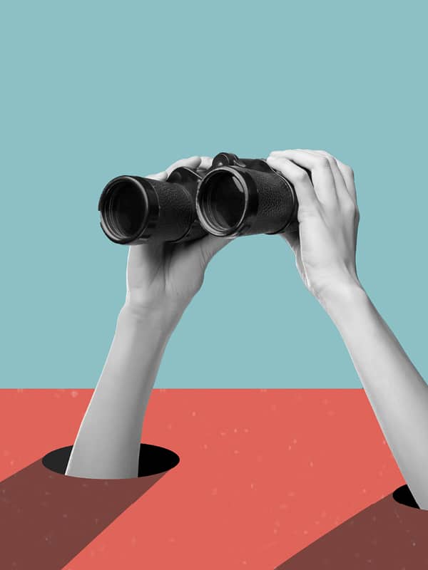 Two hands holding binoculars emerge from separate holes in a red surface, against a blue background, as if searching or observing something in the distance.